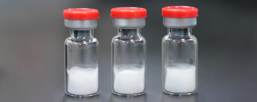 Three small glass vials with red caps each containing white powder set against a dark background jun updated   lyophilization development jun updated   lyophilization development